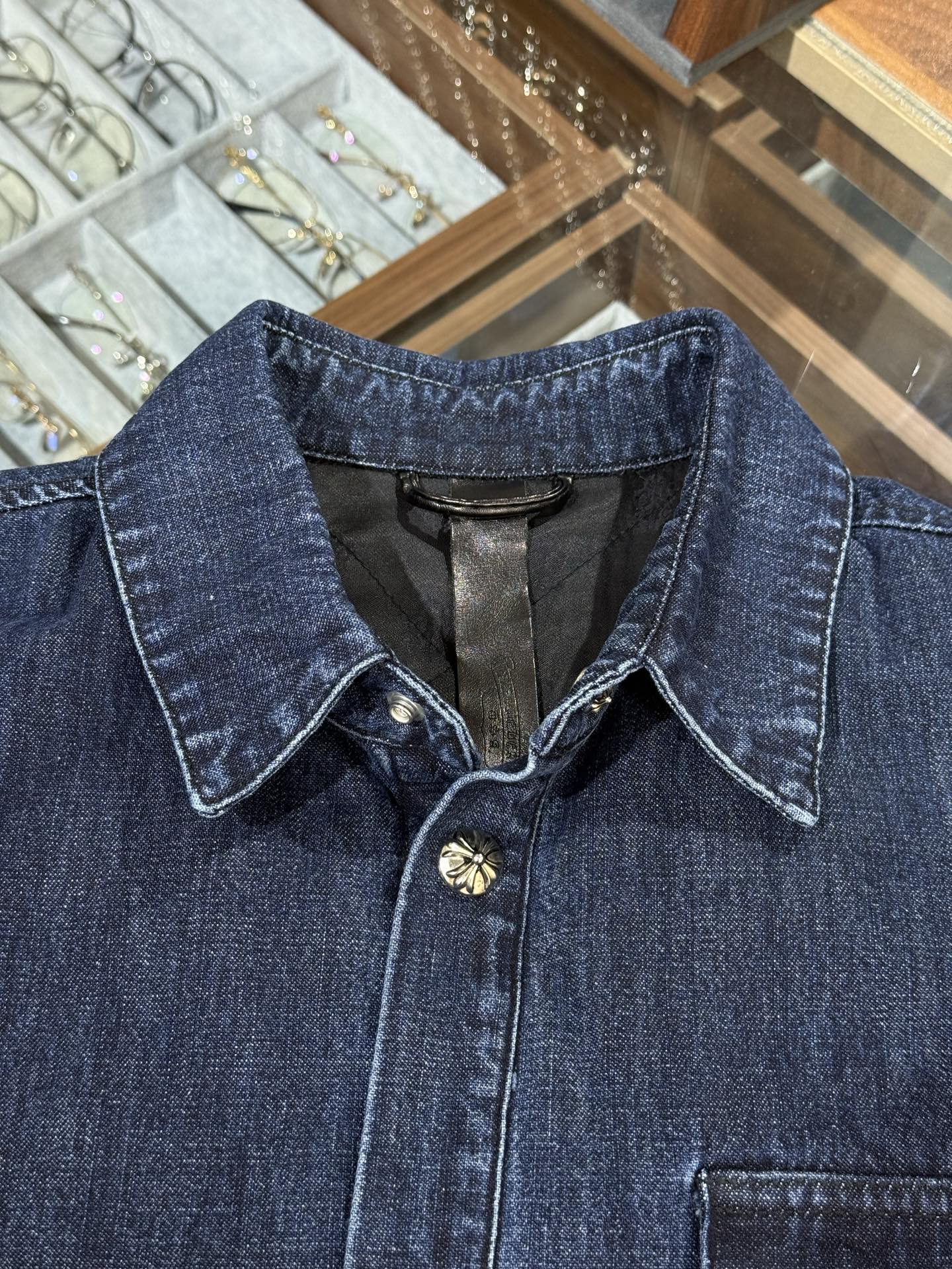 Chrome Hearts logo on the arm with Sanskrit lettering; large silver scroll and cross design on the chest; blue denim jacket. Sizes: S, M, L.