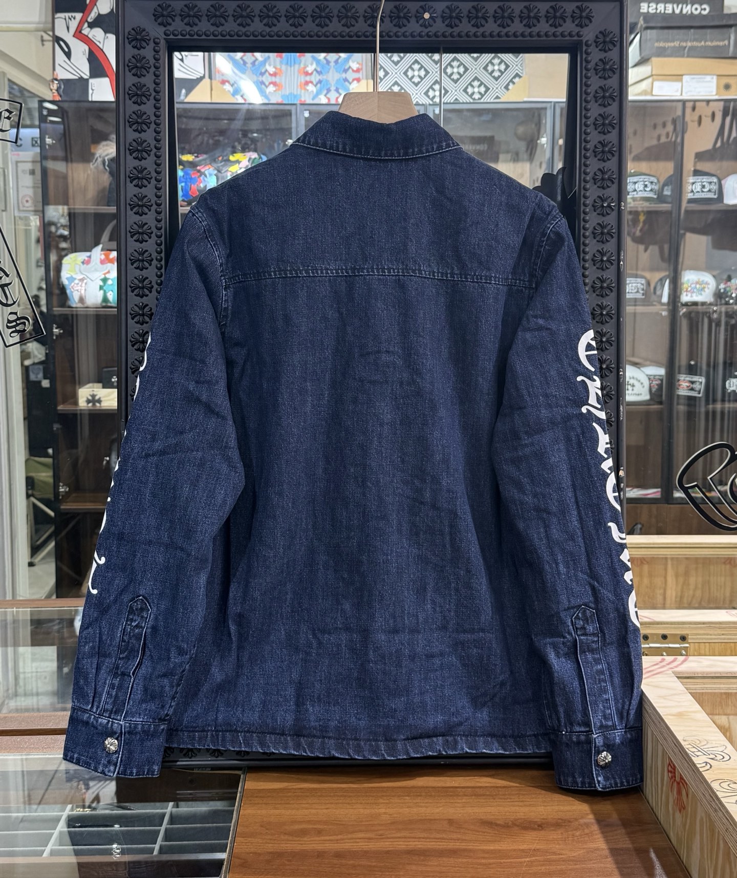 Chrome Hearts logo on the arm with Sanskrit lettering; large silver scroll and cross design on the chest; blue denim jacket. Sizes: S, M, L.